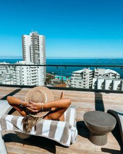 Cape Town的住宿－Home Suite Hotels Station House，坐在俯瞰大海的阳台毛巾上的女人
