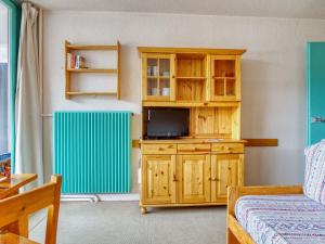 a living room with a tv and a wooden cabinet at Studio Chavière-13 by Interhome in Les Menuires