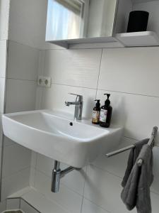 a white sink in a white tiled bathroom at Apartment in Weiden i. d. Opf. in Weiden