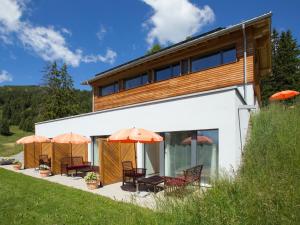 ein Haus mit orangefarbenen Sonnenschirmen auf einer Terrasse in der Unterkunft Apartment Raschainas Lenzerheide by Interhome in Sporz