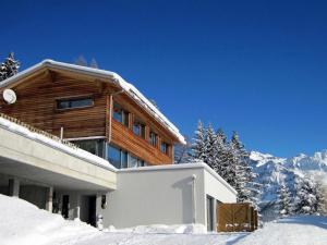 a house in the snow with mountains in the background at Apartment Raschainas Lenzerheide by Interhome in Sporz
