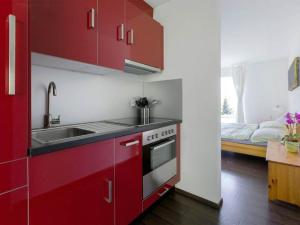 a red kitchen with a sink and a stove at Apartment Raschainas Lenzerheide by Interhome in Sporz