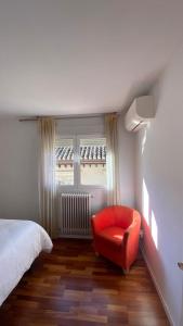 1 dormitorio con una silla roja frente a una ventana en Apartamento centro de Granada, en Granada