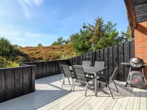 a deck with a table and chairs and a grill at Holiday Home Grita - 500m from the sea in Western Jutland by Interhome in Vejers Strand