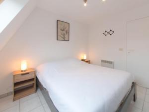 Un dormitorio con una cama blanca y dos velas en una mesita de noche. en Apartment Ter Duinen-1 by Interhome, en Bredene