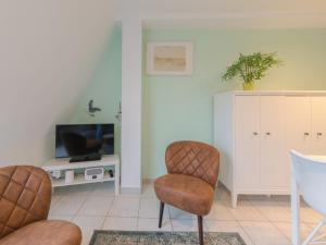 Una sala de estar con dos sillas y un televisor. en Apartment Ter Duinen-1 by Interhome, en Bredene