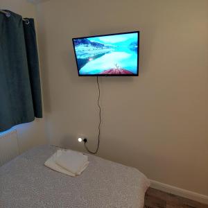 a flat screen tv hanging on a wall above a bed at EnSuite Room with private shower, walking distance to Harry Potter Studios in Leavesden Green