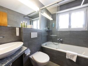 La salle de bains est pourvue d'un lavabo, de toilettes et d'une baignoire. dans l'établissement Apartment Hotel Restaurant La Tgoma by Interhome, à Lenz