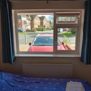 a bedroom with a window with a red car outside at EnSuite Room with private shower, walking distance to Harry Potter Studios in Leavesden Green