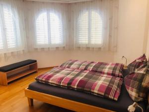 ein Schlafzimmer mit einem Bett und drei Fenstern in der Unterkunft Apartment Edelweiss C by Interhome in Leukerbad