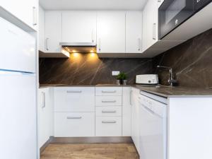 uma cozinha branca com armários brancos e um lavatório em Apartment Rodas-5 by Interhome em Salou