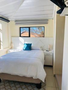ein Schlafzimmer mit einem großen weißen Bett mit einem blauen Kissen in der Unterkunft Mercy Land Guesthouse in Matatiele