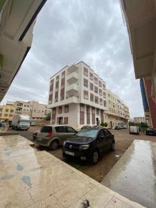 two cars parked in a parking lot in front of a building at Appartement near airport ouled tayeb in Al Hachlaf