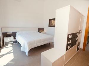 a white bedroom with a bed and a dresser at Villa Villa Perla by Interhome in Bonmont Terres Noves