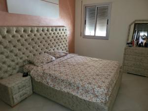 a bedroom with a large bed with a padded headboard at Appartement near airport ouled tayeb in Al Hachlaf