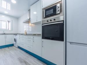 een keuken met witte kasten, een fornuis en een magnetron bij Holiday Home Montserrat by Interhome in Segur de Calafell