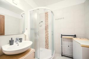 a white bathroom with a sink and a shower at D&B Lelle Apartman in Balatonlelle