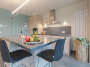 uma cozinha com um balcão com cadeiras e frutas em Apartment koningstern by Interhome em Bredene