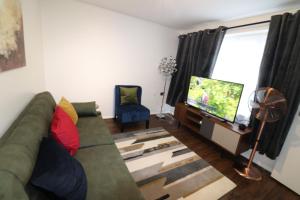 a living room with a green couch and a flat screen tv at Central Modern House, Greenhithe in Kent