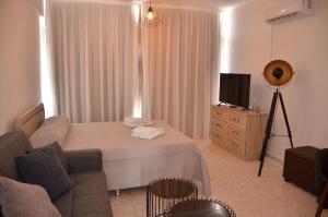 a bedroom with a bed and a couch and a television at Almyria Apartments - By IMH Travel & Tours in Paphos