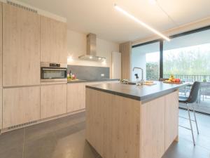 uma cozinha com armários de madeira e uma grande janela em Apartment koningstern by Interhome em Bredene