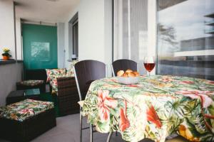 a table with a bowl of fruit and a glass of wine at D&B Lelle Apartman in Balatonlelle