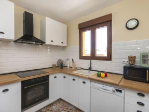 una cocina con armarios blancos y un reloj en la pared en Holiday Home Ca La Lou by Interhome, en Sils