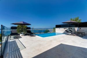a patio with a swimming pool and umbrellas at Villa Zara in Dramalj