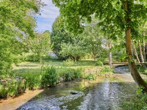a stream in a park with trees and a bridge at Studio Le laizon 1 by Interhome in Croissanville