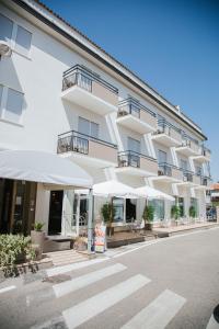 un gran edificio blanco con sombrillas delante en Hotel Laura, en Cavallino-Treporti