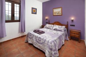 a bedroom with a bed with purple walls at Casa Rural Los Hidalgos in Tolatán