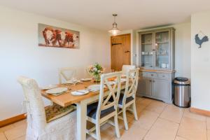 een keuken en eetkamer met een houten tafel en stoelen bij Bill's Cottage in Northleach