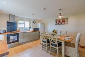 a kitchen with a wooden table and chairs and a counter at Bill's Cottage in Northleach