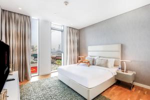 a bedroom with a white bed and a large window at Bluewater Island - Bright 2 BR Suite with Dubai Eye View by Livbnb in Dubai