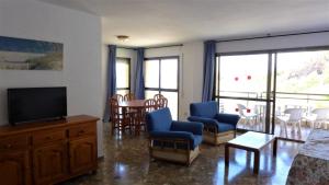 薩洛的住宿－Cala Llenguadets，客厅配有电视、椅子和桌子