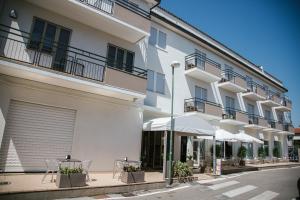 un edificio blanco con mesas y sombrillas en una calle en Hotel Laura, en Cavallino-Treporti