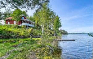a house on a hill next to a body of water at Cozy Home In motfors With Lake View in Åmotsfors