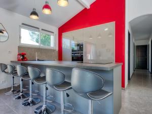 una cocina con paredes rojas y una barra con taburetes en Holiday Home Plassan by Interhome, en Lesparre-Médoc