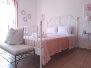 a white bedroom with a bed and a chair at Maison Du Lac in Kanoni