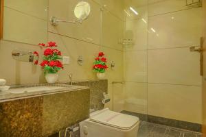 a bathroom with a toilet and a sink with red flowers at Hotel Hira Inn-10mins From Railway Station & Bus Station in Allahābād