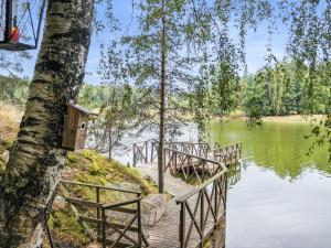a wooden bridge over a lake with a bird house on a tree at Holiday Home Pippuriranta by Interhome 