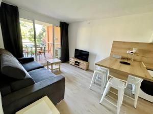 uma sala de estar com um sofá e uma mesa em BADINE BEACH 5p Plage piscine balnéo clim jardin éxotique em Hyères