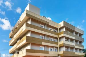 wysoki budynek apartamentowy z niebieskim niebem w tle w obiekcie ALFA HOTEL w mieście Skaramangás