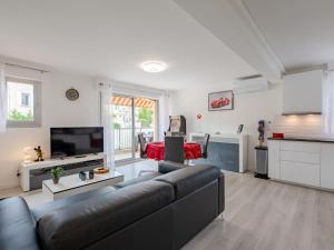 sala de estar con sofá negro y cocina en Apartment La Palmeraie II-13 by Interhome, en Sainte-Maxime