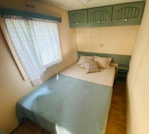 ein kleines Bett in einem kleinen Zimmer mit Fenster in der Unterkunft Monte do Bidé Private Farm Peace and Nature in Setúbal