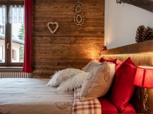 a bedroom with a wooden wall and a bed with pillows at Apartment Il Fior di Neve by Interhome in Prali