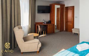 um quarto de hotel com uma cadeira e uma secretária em Hotel CARO em Poznań
