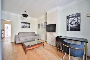 een woonkamer met een bank en een klok aan de muur bij 12.Appartement 4Pers#Sèvres-Lecourbe#Necker in Parijs