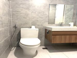 W łazience znajduje się toaleta, umywalka i lustro. w obiekcie Compass One Building - Luxury Apartments w mieście Ấp Phú Thọ