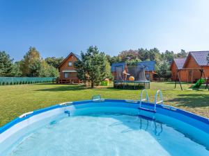 a swimming pool in a yard with a playground at Holiday Home Domki Miłe-1 by Interhome in Choczewo